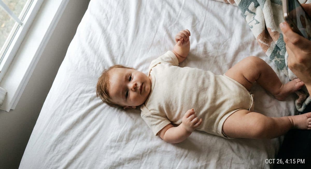 Casual photo of a baby lying on a white sheet