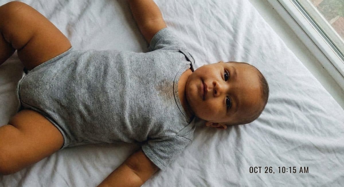 Casual photo of a baby lying on a white sheet