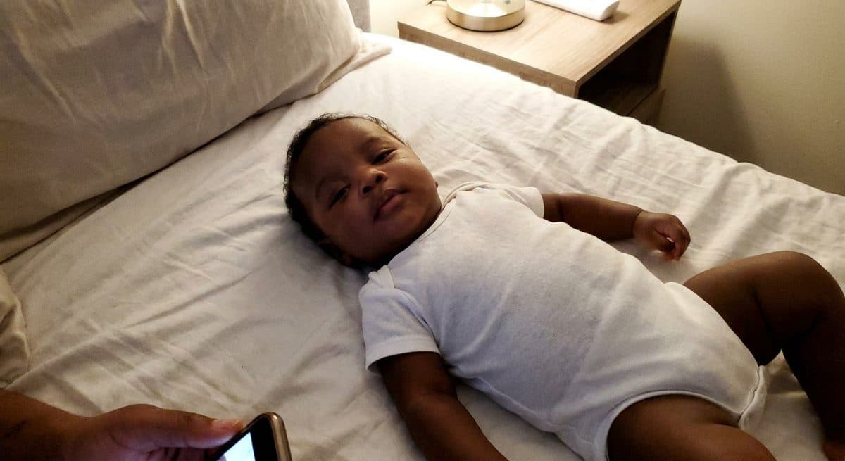 Casual photo of a baby lying on a white sheet