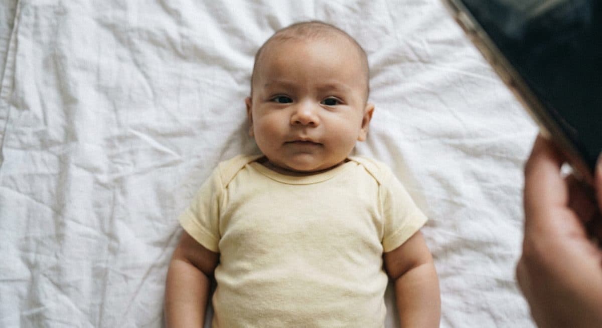 Casual photo of a baby lying on a white sheet