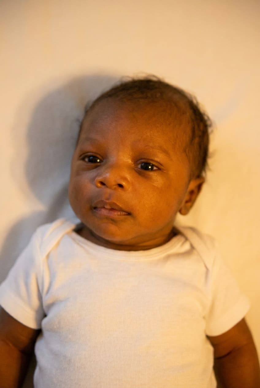 newborn photo with a shadow behind the head, warm filter, and oversized off-centre head — would be rejected